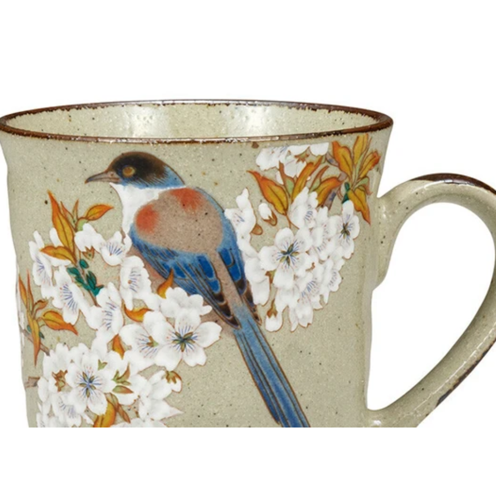 Ceramic mug with a bird and floral design on a beige background