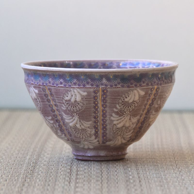 Decorative ceramic bowl with intricate patterns on a textured surface
