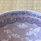 Close-up of a ceramic bowl with floral patterns on a textured beige background