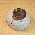 Ceramic container with brown lid on a woven mat