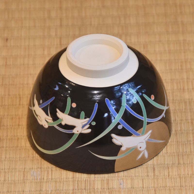 Ceramic bowl with bird design on a woven mat