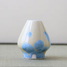 Matcha whisk stand with blue floral patterns on a neutral background