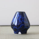 Blue Matcha whisk stand on a textured surface with a neutral background
