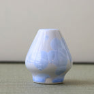 Matcha Whisk stand with blue floral patterns on a neutral background