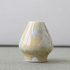 Yellow ceramic vase with white floral patterns on a neutral background