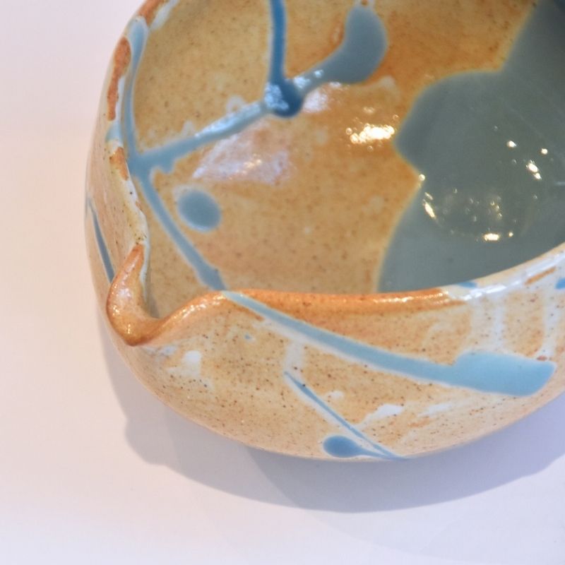 Ceramic bowl with blue and orange glaze on a white background