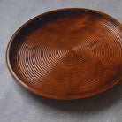 Brown wood tray with textured surface on a gray background