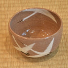 Ceramic bowl with brown and white design on a woven mat