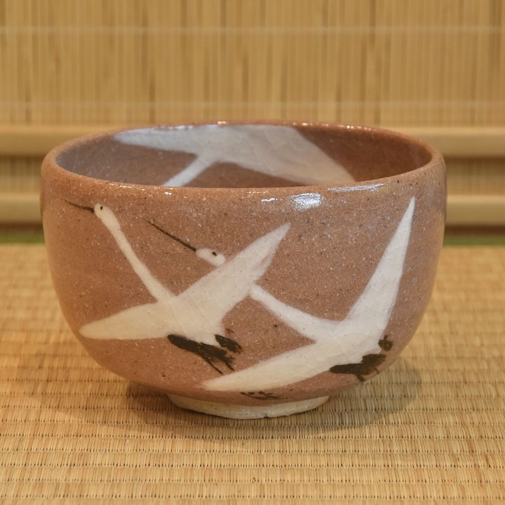 Ceramic bowl with bird design on a woven mat