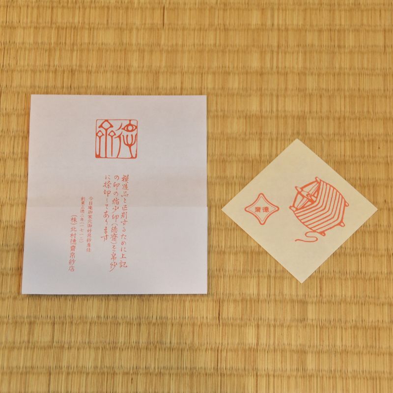 Two red stamps on white paper and beige card against a bamboo mat background