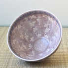 Ceramic bowl with floral patterns on a woven mat
