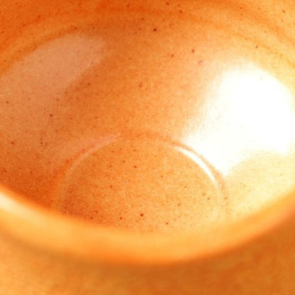 Enlarged photo of Nara Tea Co.'s Akashino Matcha Tea Bowl with a slightly rough texture and elegant orange color, showing the inside of the bowl.