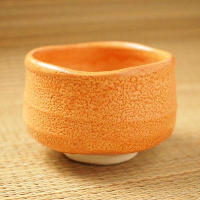 Akashino Matcha Tea Bowl from Nara Tea Co. with a slightly rough texture and an elegant orange color, seen from the side diagonally above the front.