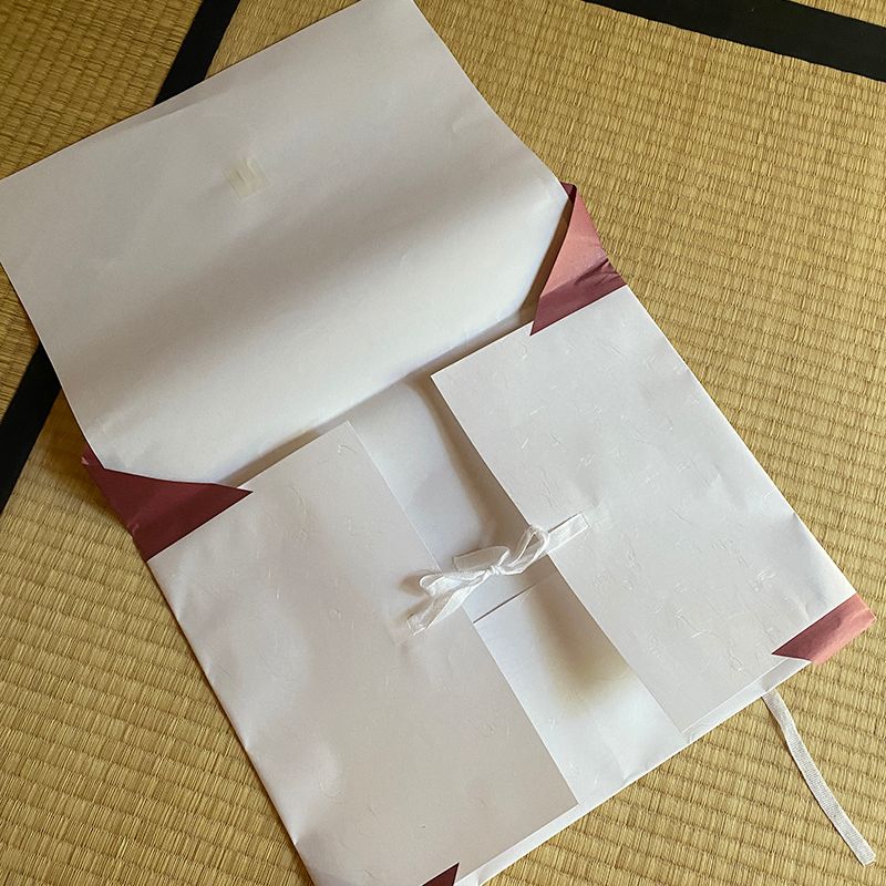 Nara Tea Co.'s 10-sheet Tatoushi l kimono Storage Paper with Strings product package opens one sheet to reveal knots in the interior strings.