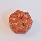 Orange fabric wrap with gold and green floral patterns on a white background