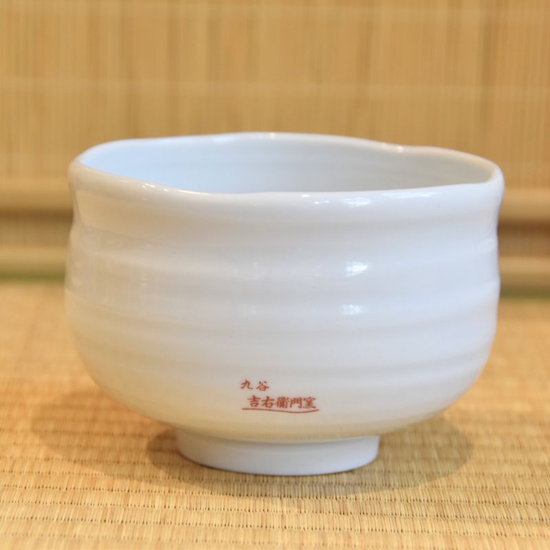 White ceramic cup with red text on a woven mat