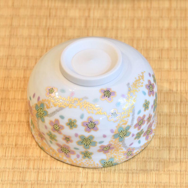 Decorative ceramic bowl with floral patterns on a bamboo mat