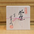 Wooden box with Japanese calligraphy and seals on a bamboo background