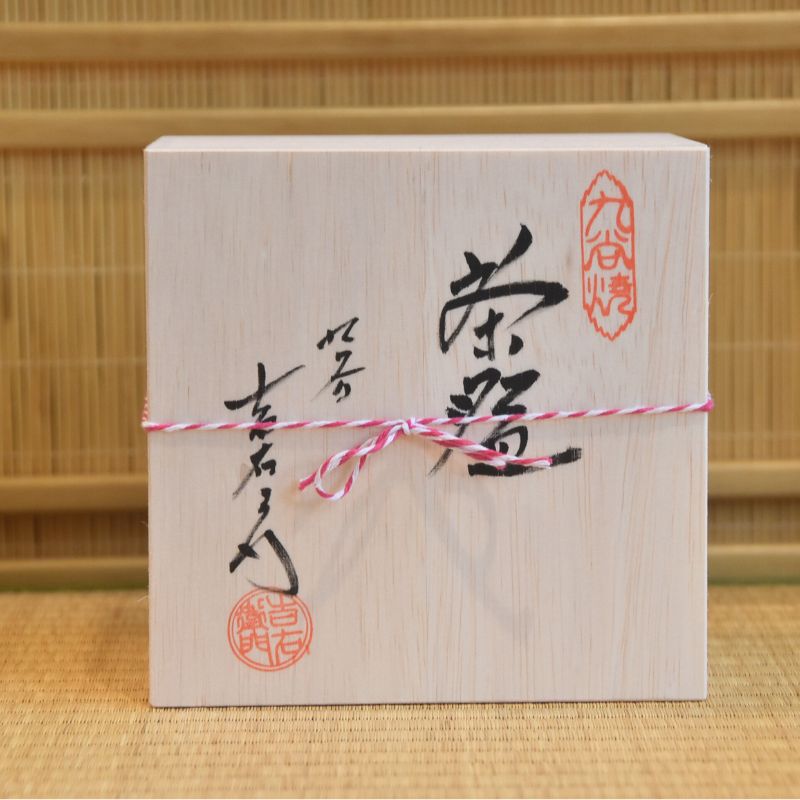 Wooden box with Japanese calligraphy and seals on a bamboo background