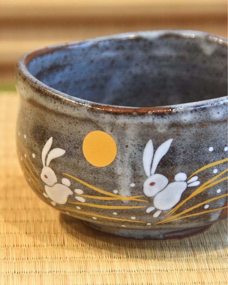 Close-up of a ceramic bowl decorated with illustrations of a rabbit and the moon.