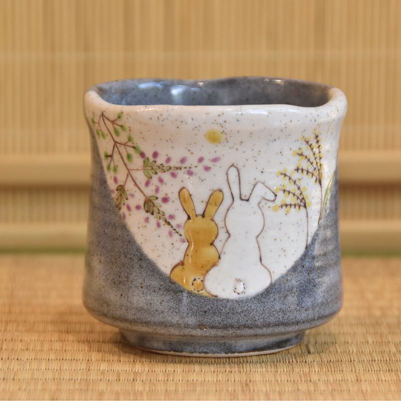 Ceramic cup with rabbit design on a bamboo mat background