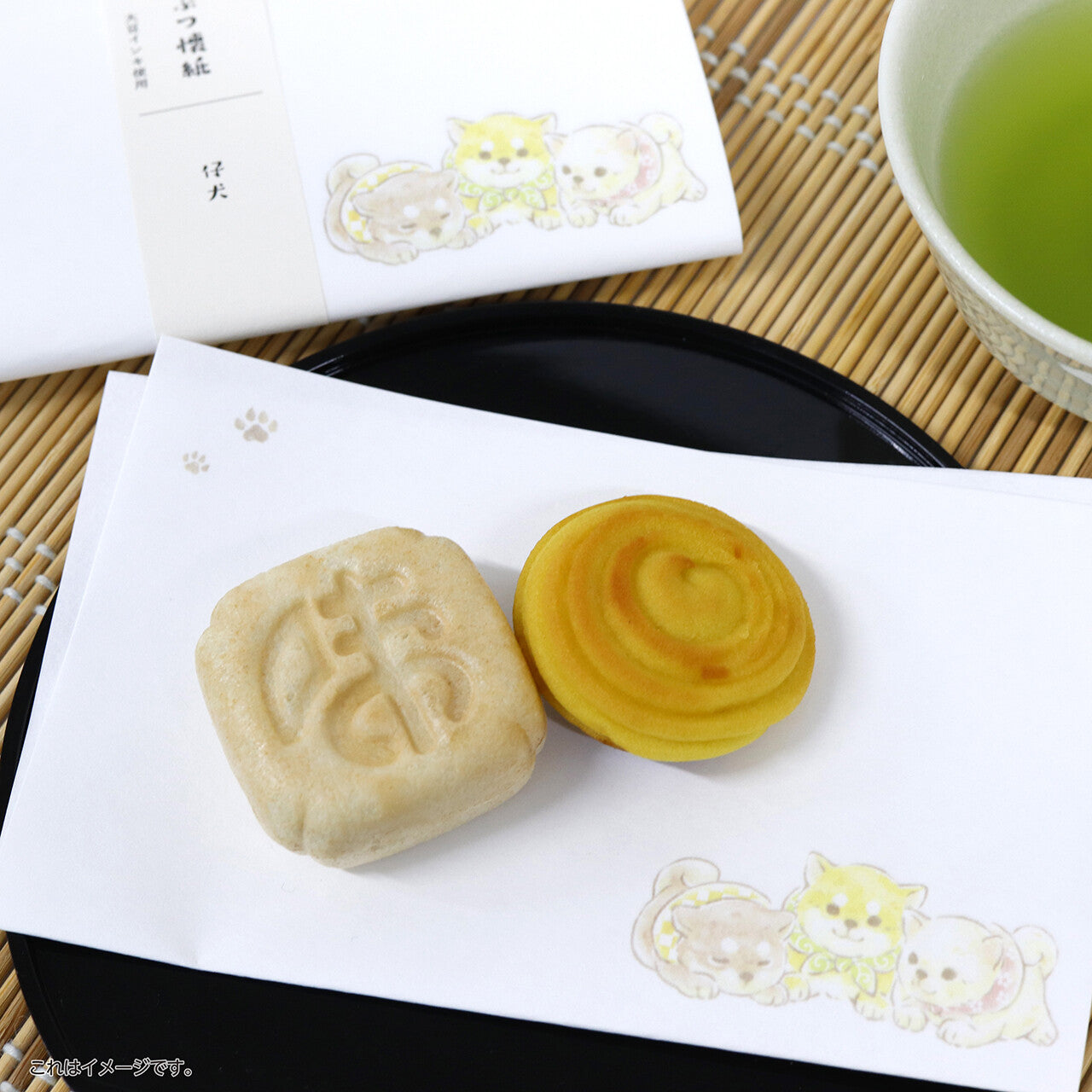 Two traditional Japanese sweets on a white napkin with a cup of green tea in the background.