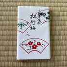 White box with red floral designs and black text on a woven mat background