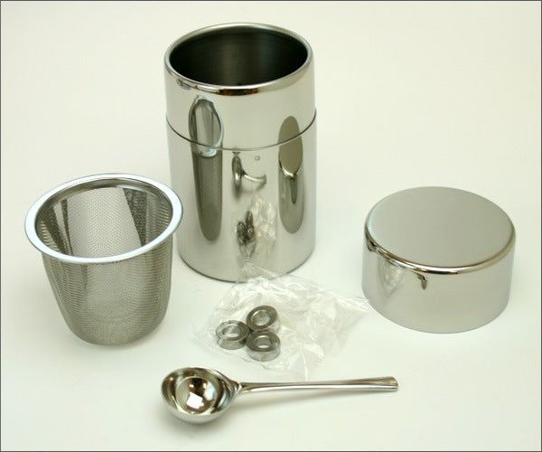 A stainless-steel matcha sifter can with a set of three round stainless-steel balls and a measuring spoon, displayed on a white background.