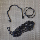 Set of black metal hooks and chains on a textured beige surface