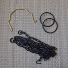 Set of black chains, gold hook, and black rubber bands on a textured gray surface