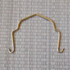 Brass metal hook on a textured gray background