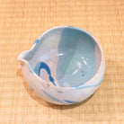 Ceramic bowl with blue and white design on a woven mat