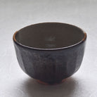 Dark brown ceramic bowl on a light gray background