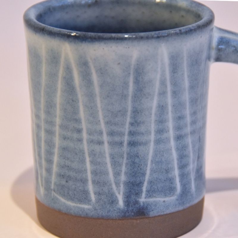 Blue ceramic mug with white lines on a white background