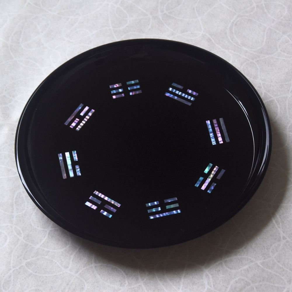 Black circular object with colorful patterns on a textured white background