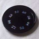 Black circular object with colorful patterns on a textured white background