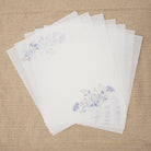Set of white paper sheets with floral designs on a beige fabric background