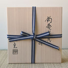 Gift box with a blue ribbon and black text on a neutral background