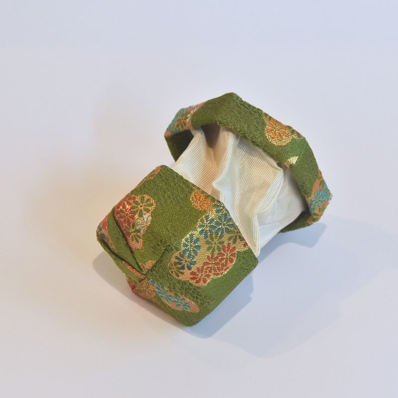 Green fabric box with floral patterns on a white background