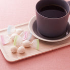 Cup of coffee on a saucer with pastel wasanbon sweets candies on a pink background