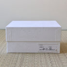 White textured box with a label on a beige surface