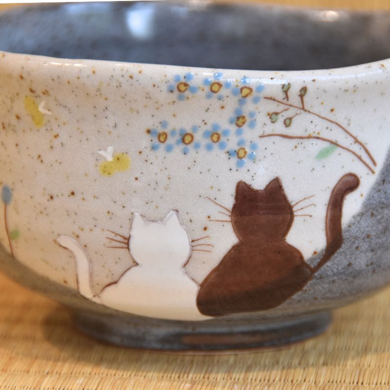 Ceramic bowl with cat illustrations on a wooden surface