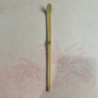 Long, thin wooden object on a textured surface with floral patterns