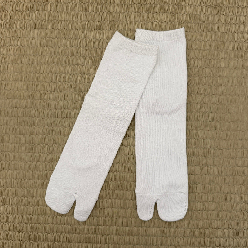 A pair of white tabi socks laid flat on a textured beige woven mat background.