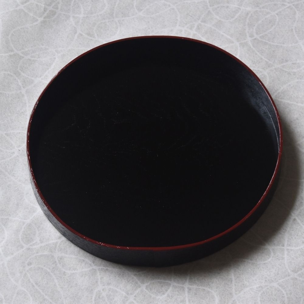 Black round tray on a textured gray surface