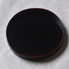 Black round tray on a textured gray surface
