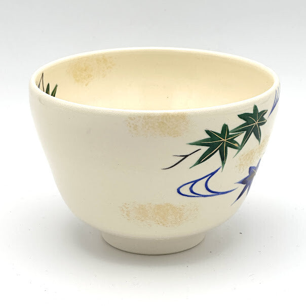 Reverse view of the Aomomiji Kyo Ware chawan showing a smaller green maple leaf and flowing water motif on the ivory glaze