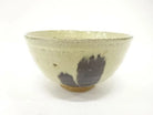 Back view of the pre-owned matcha bowl showing its restrained cream and muted green glaze, rounded form, and exposed clay foot.