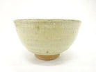 Back view of the pre-owned matcha bowl showing its restrained cream and muted green glaze, rounded form, and exposed clay foot.