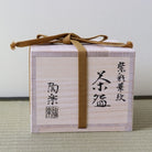 A light natural wood presentation box tied with a brown ribbon, featuring black Japanese calligraphy on the front, set against a neutral background.